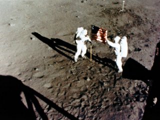 Aldrin and Armstrong raise the Stars and Stripes rather too close to the LM. (Image credit: NASA)